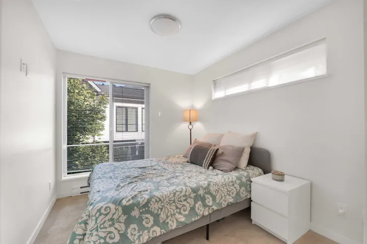 Bedroom with light carpet and a baseboard heating unit