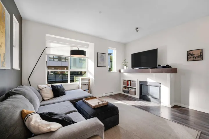 Living area featuring a fireplace with flush hearth, wood finished floors, and a baseboard heating unit