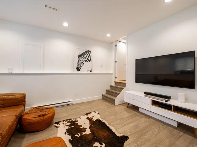 Living room with light wood-style floors, recessed lighting, baseboard heating, and stairway
