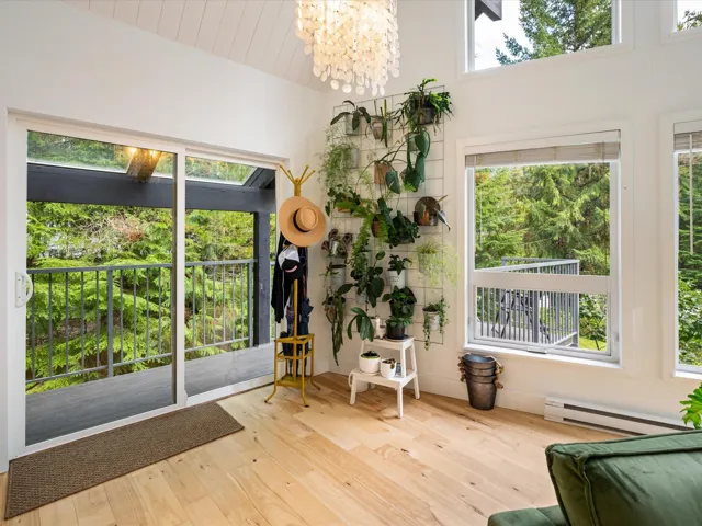 Living area featuring healthy amount of natural light, light wood-style flooring, a chandelier, and a baseboard radiator