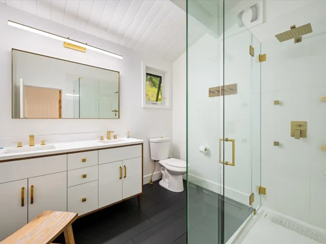 Full bath with double vanity, a shower stall, and dark tile patterned flooring