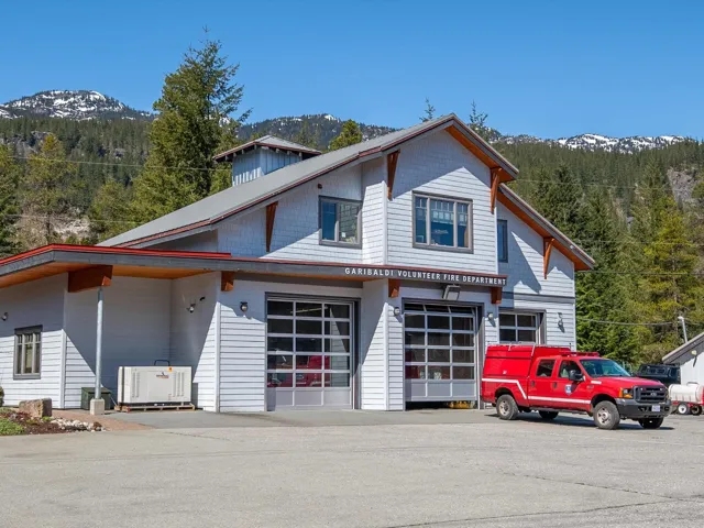 View of front of home featuring a garage, a mountain view, driveway, and a view of trees