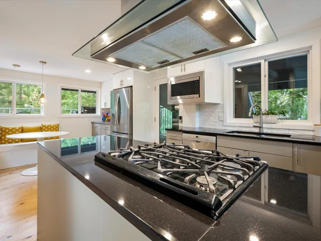 Kitchen with range hood, appliances with stainless steel finishes, white cabinetry, tasteful backsplash, and dark stone countertops