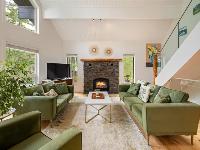 Living room featuring a fireplace, wood finished floors, high vaulted ceiling, and a wooden ceiling with exposed beams