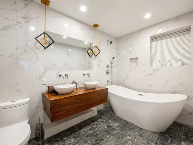 Full bath featuring a freestanding tub, double vanity, dark marble finish floors, tile walls, and recessed lighting