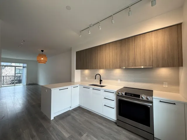 Kitchen with a peninsula, light countertops, modern cabinets, stainless steel electric stove, and a sink