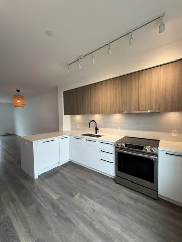 Kitchen with modern cabinets, track lighting, electric range, light countertops, and a sink