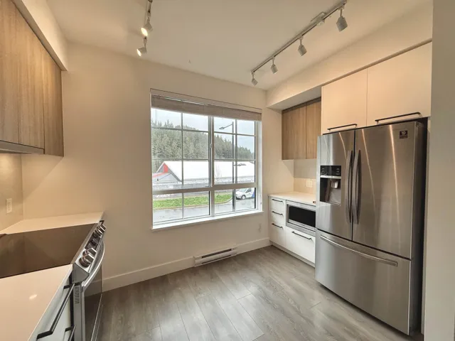 Kitchen with track lighting, modern cabinets, light countertops, appliances with stainless steel finishes, and baseboard heating