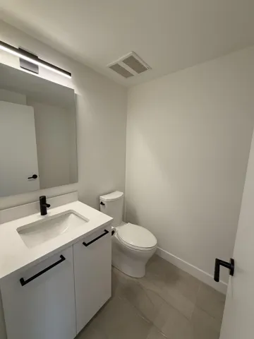 Bathroom featuring vanity, visible vents, baseboards, and toilet