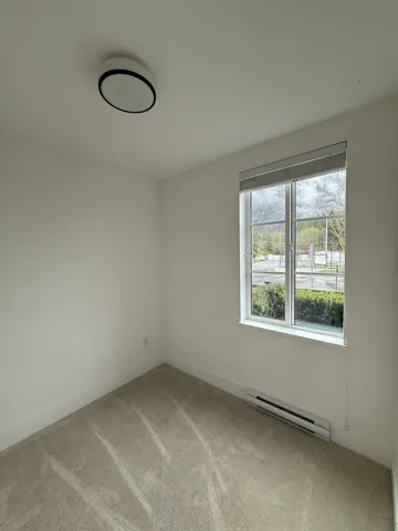 Carpeted empty room with baseboard heating and baseboards