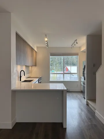 Kitchen with stainless steel fridge with ice dispenser, light countertops, a sink, and track lighting