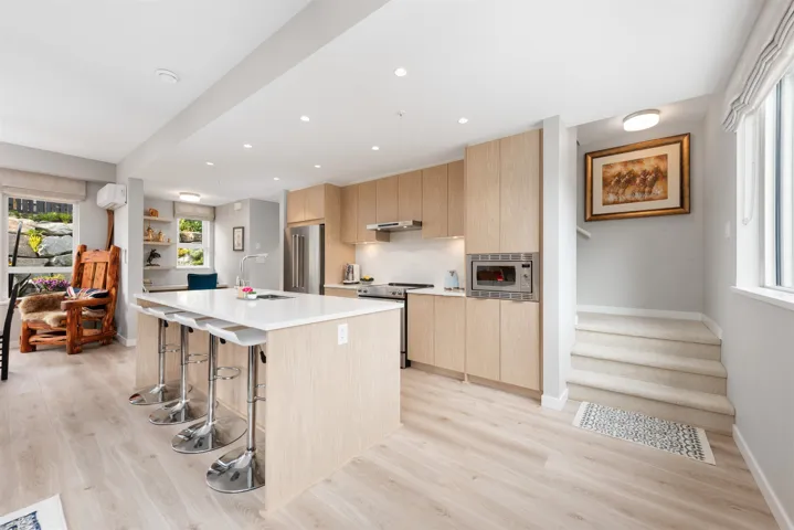 Kitchen featuring appliances with stainless steel finishes, light brown cabinetry, a breakfast bar area, modern cabinets, and light wood-type flooring