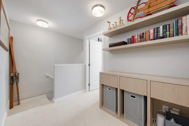 Landing and storage with light carpet and baseboards. Open concept office potential