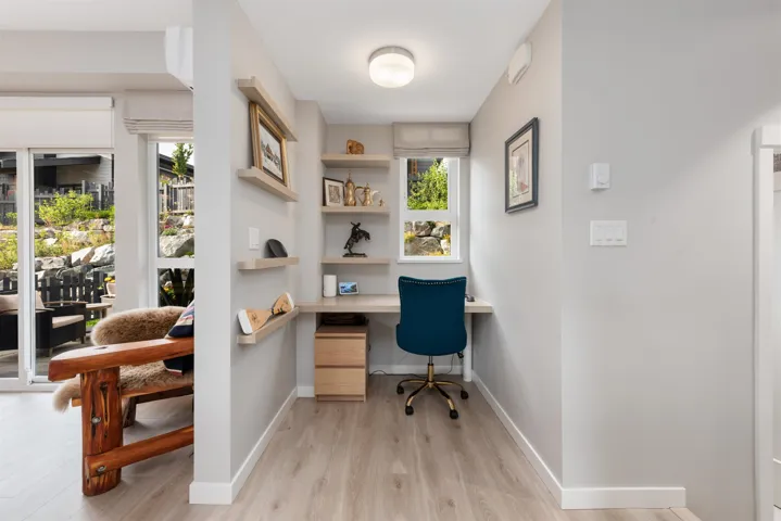 Home office with built in desk, light wood-style flooring, and healthy amount of natural light