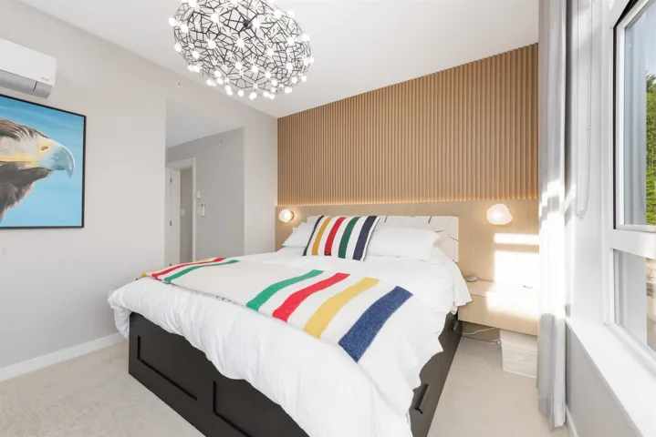 Bedroom with an AC wall unit, light carpet, and a chandelier