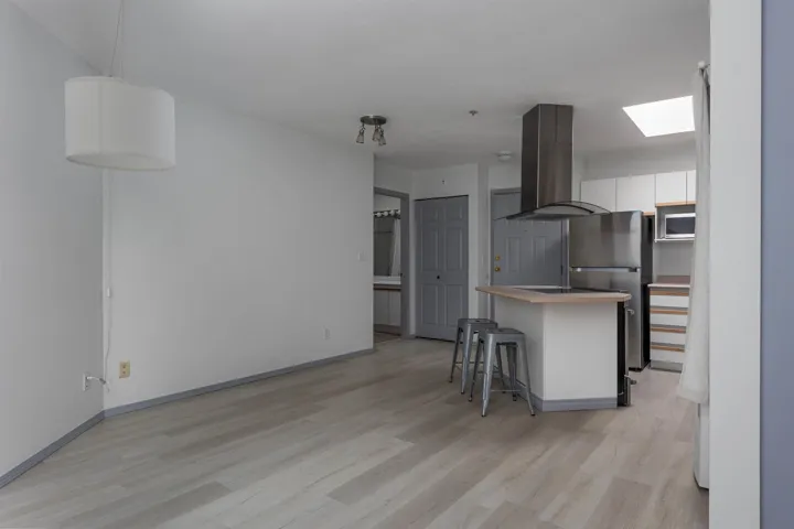 Kitchen featuring a breakfast bar area, island range hood, a skylight, stainless steel appliances, and light wood-style flooring