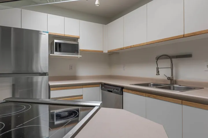 Kitchen featuring white cabinets, stainless steel appliances, light countertops, and modern cabinets