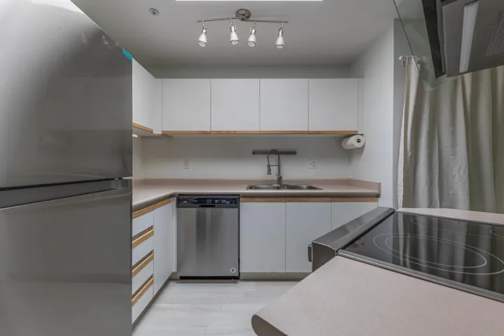 Kitchen featuring stainless steel appliances, white cabinets, range hood, and light countertops