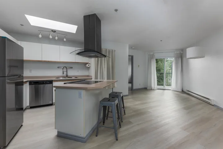 Kitchen with white cabinetry, island exhaust hood, freestanding refrigerator, baseboard heating, and dishwasher