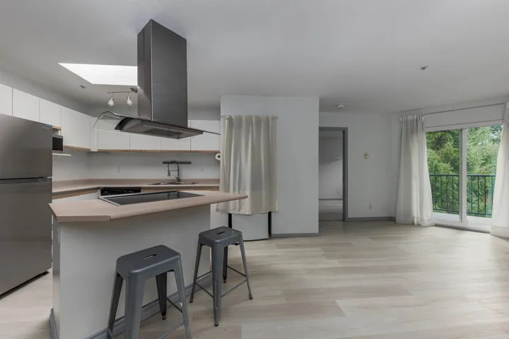 Kitchen featuring freestanding refrigerator, island exhaust hood, white cabinets, a kitchen breakfast bar, and a center island