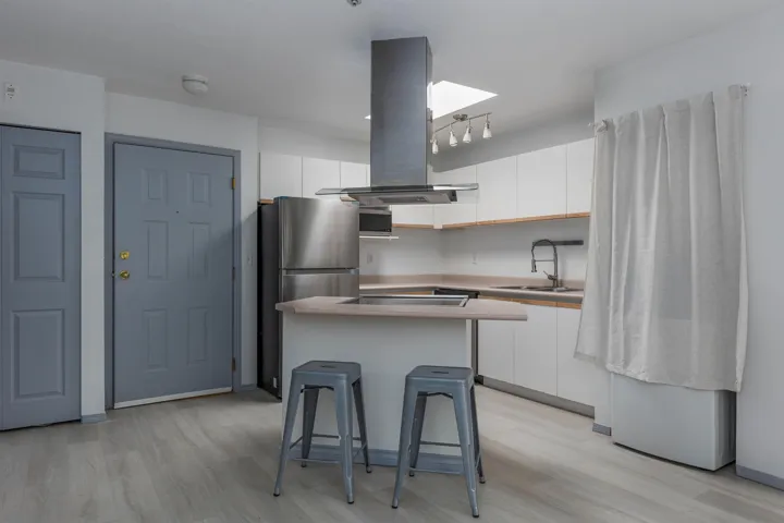 Kitchen with island range hood, a kitchen bar, a kitchen island, light wood-style floors, and freestanding refrigerator