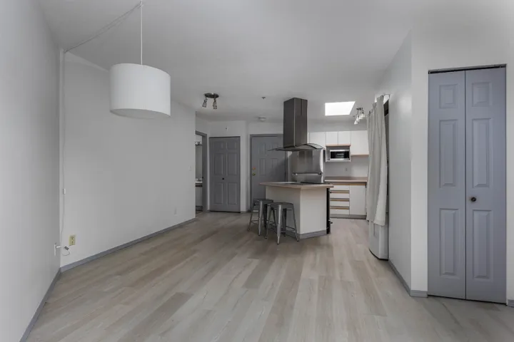 Kitchen featuring a kitchen breakfast bar, island range hood, white cabinetry, light wood-style flooring, and a center island