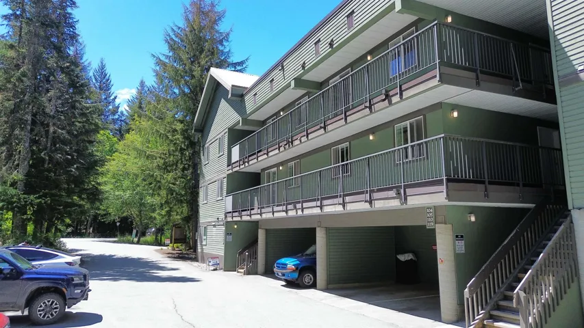 Multi-story building featuring green siding and multiple balconies with dark railings