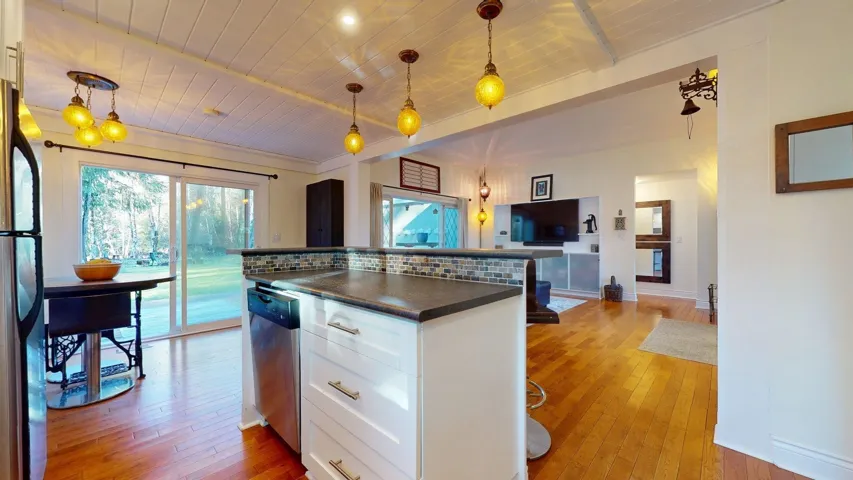 Kitchen with dark countertops, white cabinetry, light wood-style flooring, a kitchen island, and a wood ceiling with exposed beams