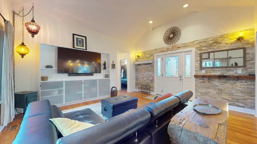 Living area featuring lofted ceiling, light wood finished floors, and recessed lighting
