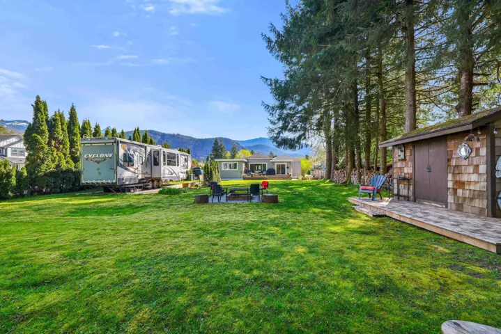 Expansive grassy yard featuring a wood-shingle sided shed with an attached wooden deck