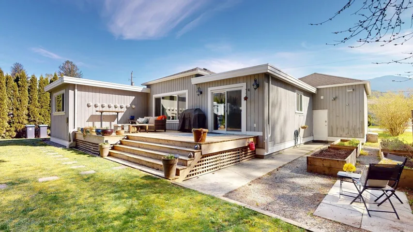 Rear view of property featuring a garden, a deck, and a yard