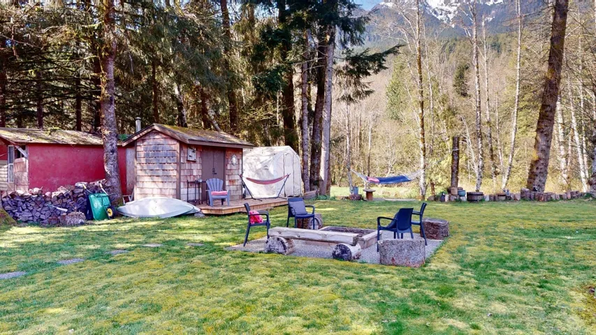View of grassy yard featuring a storage unit, a fire pit, and a patio area
