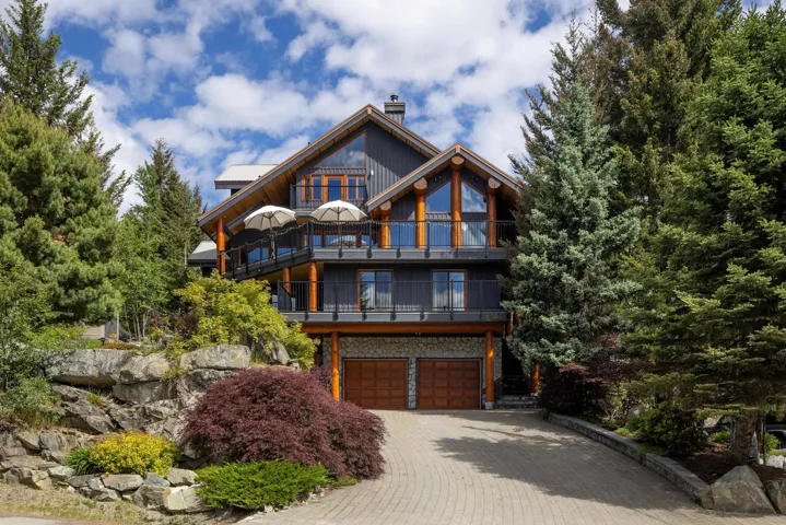Multi-level residence featuring a dark wood-paneled exterior, exposed timber beams, and expansive glass railings
