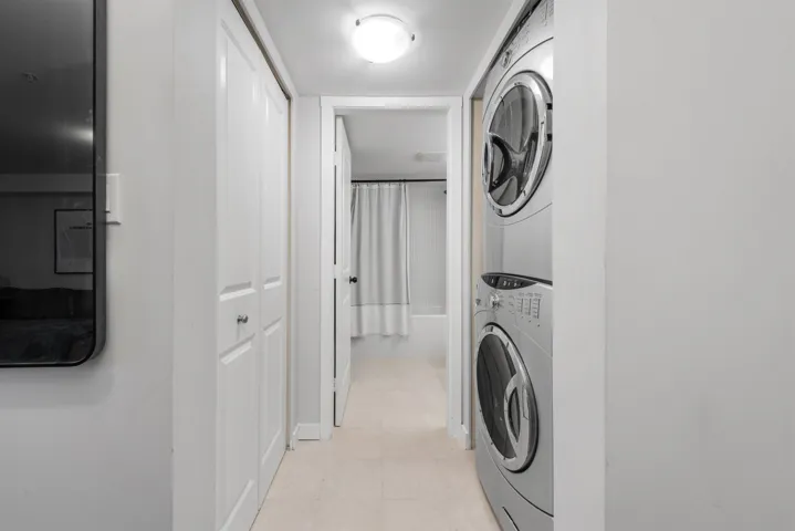 Laundry area with laundry area, light floors, and stacked washer / drying machine