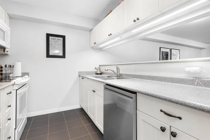 Kitchen featuring dishwasher, dark tile patterned flooring, electric range, and white cabinets