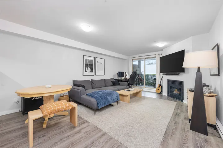 Living room featuring wood finished floors, a glass covered fireplace, and baseboards