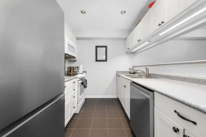 Kitchen with white cabinetry, baseboards, appliances with stainless steel finishes, and light countertops