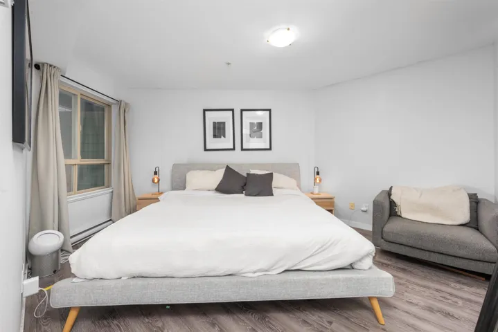 Bedroom with a baseboard heating unit and wood finished floors