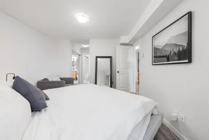 Bedroom with ensuite bath, baseboards, and dark wood-type flooring