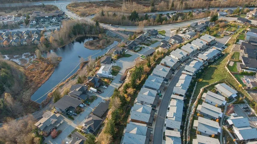 Aerial view of property and surrounding area featuring nearby suburban area and a large body of water