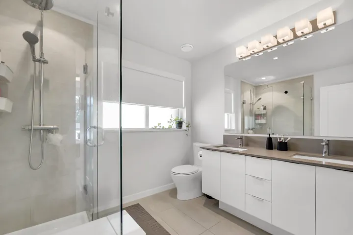 Bathroom with a shower stall, light tile patterned floors, double vanity, and recessed lighting