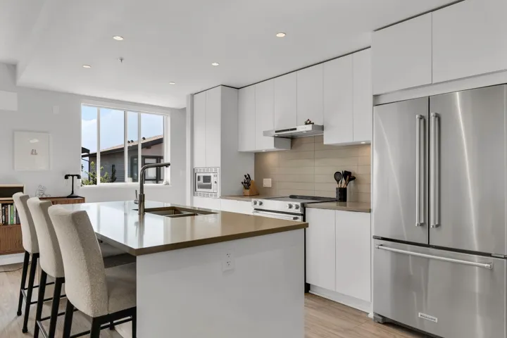 Kitchen featuring stainless steel appliances, recessed lighting, white cabinetry, a center island with sink, and backsplash