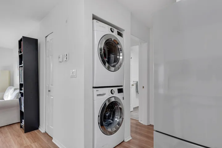Clothes washing area featuring light wood-type flooring, stacked washer / dryer, and laundry area