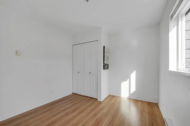 Unfurnished bedroom featuring a baseboard radiator, light wood-style flooring, and a closet