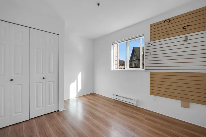 Unfurnished bedroom with a baseboard radiator, a closet, and wood finished floors