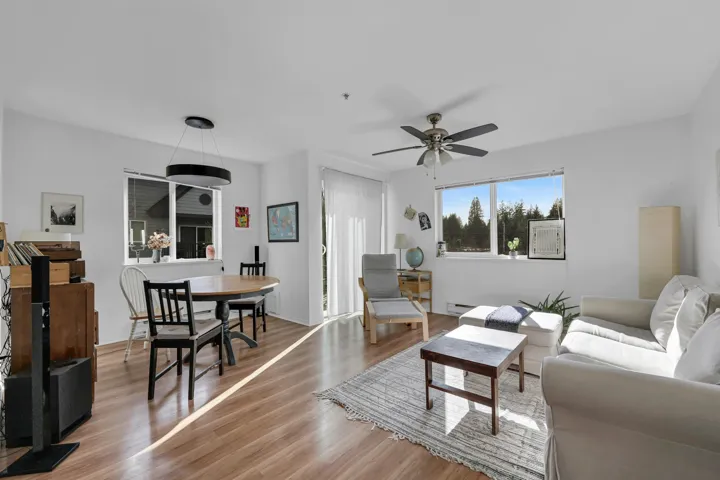 Living area with a baseboard radiator, light wood-style flooring, and a ceiling fan