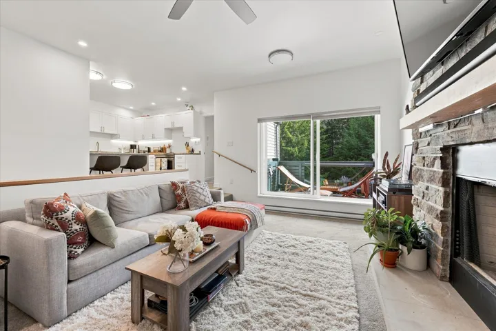 Stone-clad fireplace with wood mantel, large sliding glass door, recessed lighting, and a partial wall with a wood cap