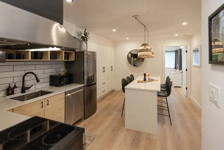 Kitchen featuring a sink, range hood, modern cabinets, and stainless steel appliances