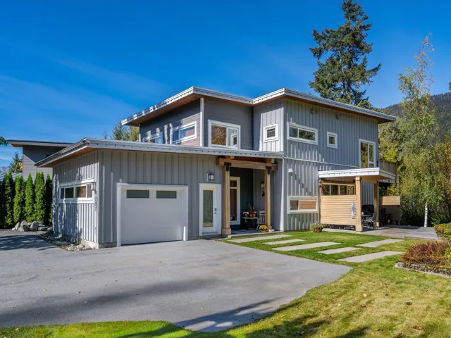 View of front of property featuring board and batten siding, a front yard, a garage, and asphalt driveway
