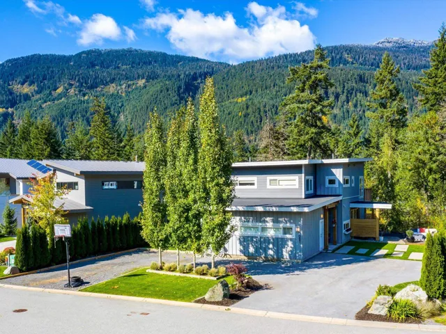 View of front facade with a view of trees, a mountain view, driveway, and a front lawn